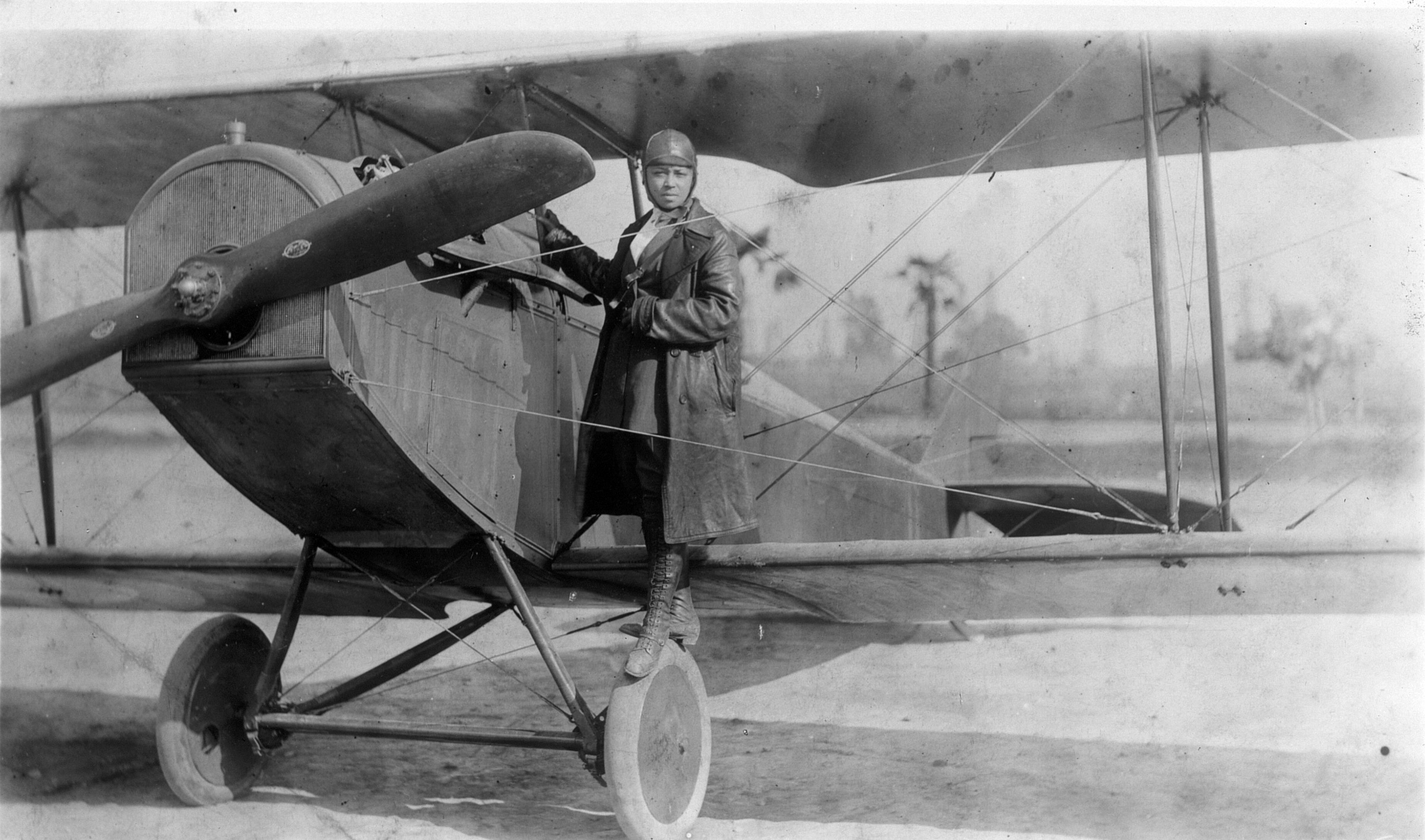 Bessie Coleman standing on the wheel of her biplane, 1922.